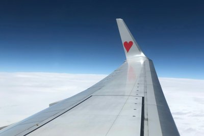 Foto von Flugzeug-Flügel mit kleinem roten Herz über den Wolken